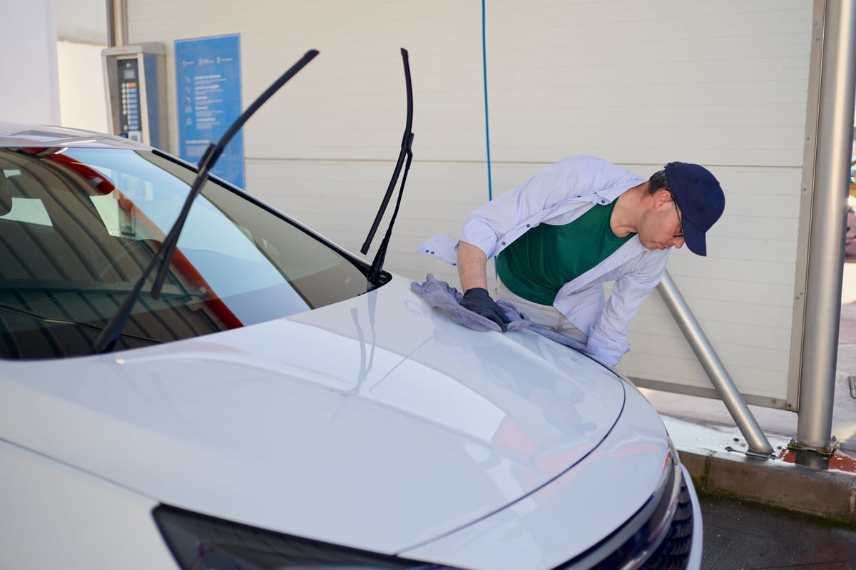 Detailer drying a white car hood with a microfiber cloth