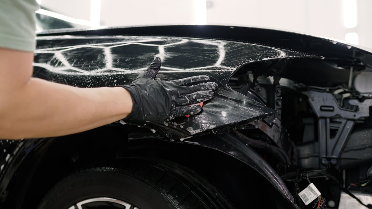 Detailer washing a vehicle with a sponge and detergent