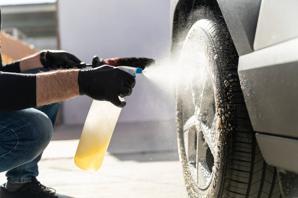 Detailer cleaning a vehicle wheel and tyre with a spray solution