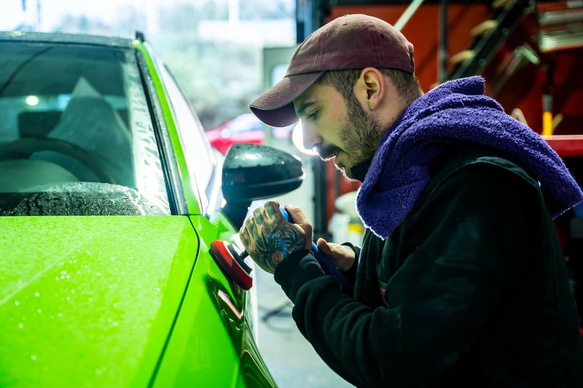 Technician polishing a car's paint to a flawless, mirror-like finish